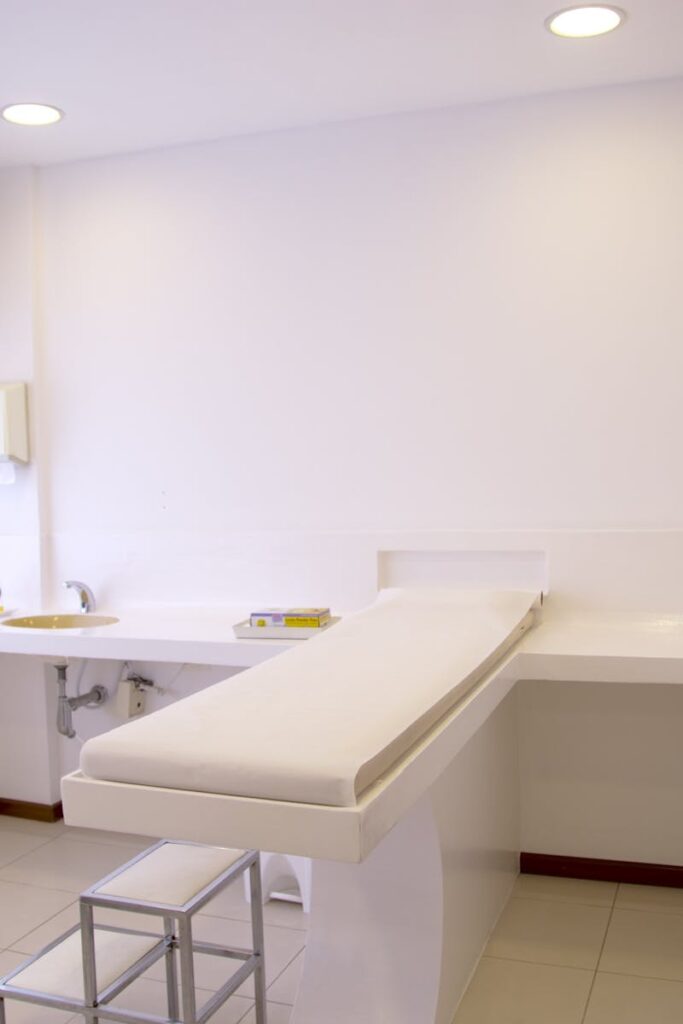 Home Minimalist white clinic room with examination table and furniture.